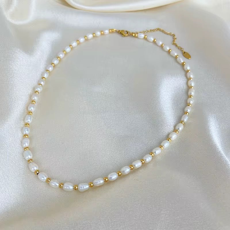 Pearl necklace with gold beads on a white satin background